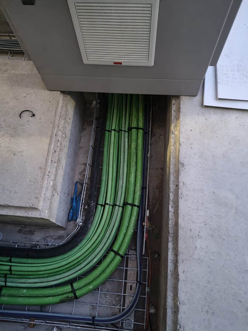 Zanja con cables de potencia sobre bandeja bajo un cuadro eléctrico