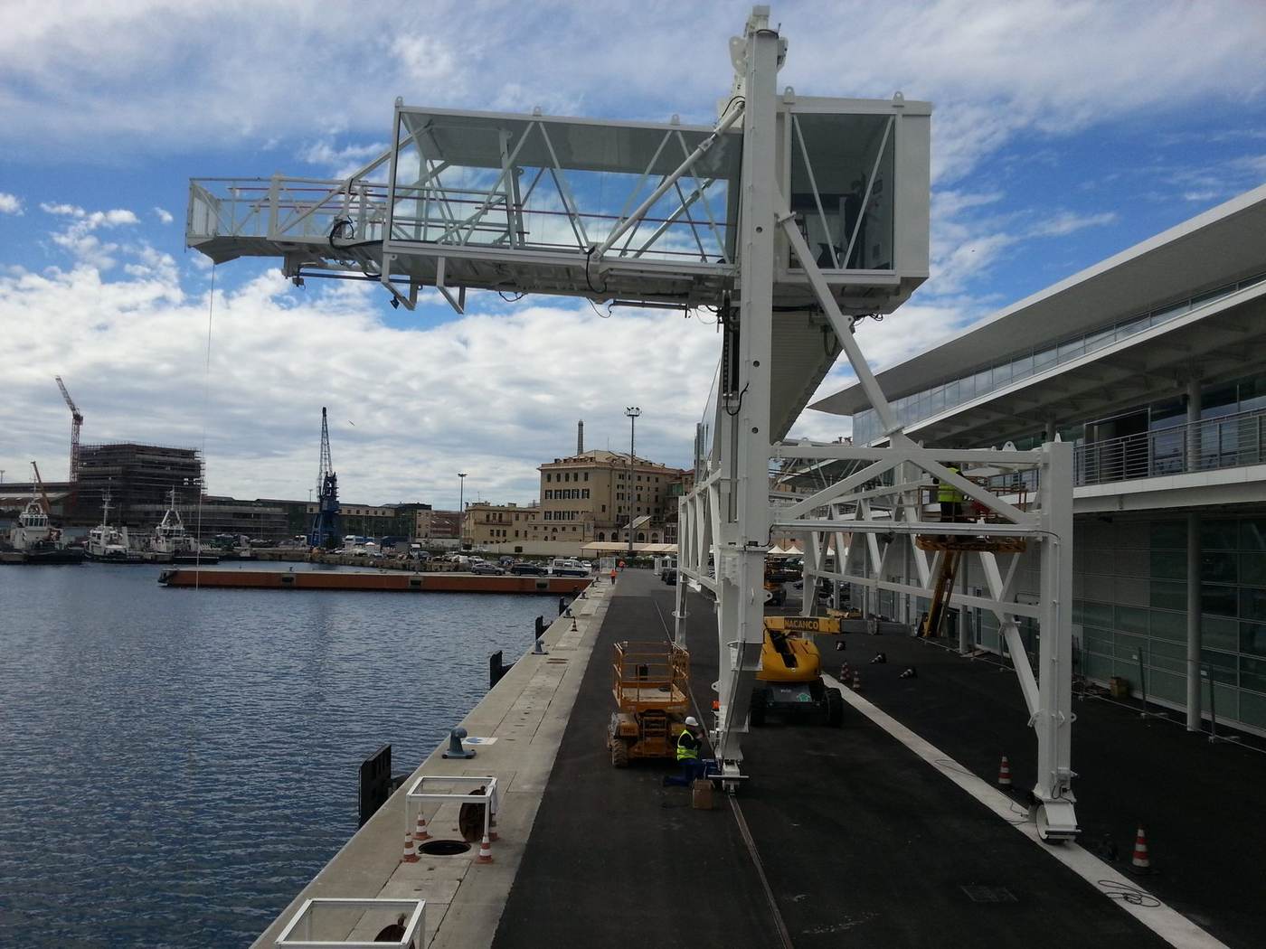 Pasarela de embarque de puerto montada sobre el muelle, con la cabina de mando y el terminal de cruceros al lado